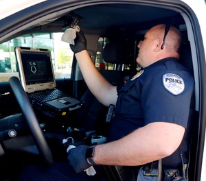 Richardson police officer Dustin Penland uses gloves as he wipes down the interior of his vehicle with disinfectant wipes at the start of his shift change, Wednesday, April 8, 2020.