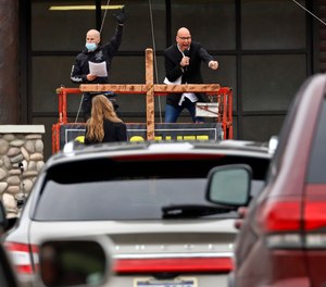 Paster Bruce Schafer, top right, preaches from a scissor lift during the first of two drive-in Easter services held by Grace Life Church in a parking lot in Monroeville, Pa., Sunday, April 12, 2020.