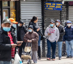 People wear face masks to protect against the coronavirus as they stand on line to grocery shop, Tuesday, April 14, 2020, in Corona neighborhood of the Queens borough of New York.