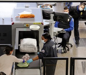 TSA agents wear masks as they screen passengers at Seattle-Tacoma International Airport Wednesday, April 15, 2020, in SeaTac, Wash. A whistleblower has filed a complaint claiming that the TSA has been hoarding 1.4 million N95 respirators despite instructing its employees to wear surgical masks.