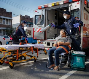 FDNY paramedics Elizabeth Bonilla, left, and Keith Kahara, right, prepare to load a patient on oxygen into their ambulance on an emergency call, Wednesday, April 15, 2020, in the Bronx borough of New York. (AP Photo/John Minchillo)