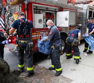 FDNY personnel disrobe from their protective equipment after an emergency call at Cobble Hill Health Center, Friday, April 17, 2020, in the Brooklyn borough of New York. New York City Mayor Bill de Blasio has announced that health insurance for families of city workers who died from COVID-19, including first responders, will be extended for 45 days. (AP Photo/John Minchillo)