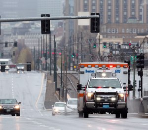 An ambulance on a call drives on Commonwealth, Ave., Friday, April 24, 2020, in Boston. Boston 911 callers now have the option to speak with a physician rather than send an ambulance, a measure implemented to prevent emergency rooms from overflowing during the COVID-19 pandemic.