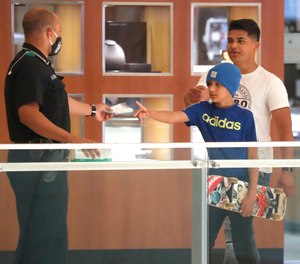 A police officer hands young shoppers masks to wear while walking inside the Galleria Dallas mall in Dallas, Monday, May 4, 2020. This is the first time this mall has opened amid the concerns of the spread of COVID-19.