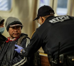 A New York Police officer attempts to help a man on the Coney Island Stillwell Avenue subway platform after it was closed for disinfecting operations, Wednesday, May 6, 2020, in the Brooklyn borough of New York. (AP Photo/Frank Franklin II)