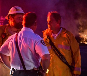 In this Wednesday, May 6, 2020 photo, South Walton Fire Chief Ryan Crawford, right, speaks to Walton County Fire Rescue EMS Chief Tracey Vause, foreground, and an unidentified firefighter as they respond to a fire at Santa Rosa Beach near Highway 98 in Walton County, Fla. Three U.S. senators have sent a letter to Vice President Mike Pence, leader of the White House Coronavirus Task Force, requesting PPE and adequate testing methods for firefighters battling wildfires during the pandemic.