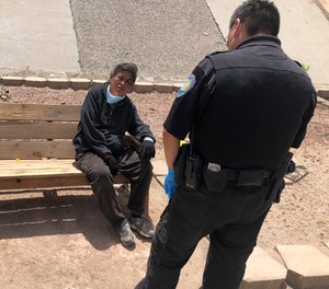 Gallup Police Officer J. Soseeah, right, checks on the health of a homeless woman in Gallup, N.M., Thursday, April 7, 2020. (AP Photo/Morgan Lee)