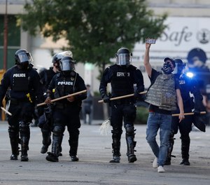A protester walks with police officers during a protest over the deaths of George Floyd and Breonna Taylor, Saturday, May 30, 2020, in Louisville, Ky.