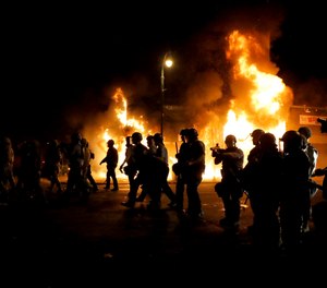 Minneapolis Police walk together while pushing protesters back away from a structure fire, Saturday, May 30, 2020, in Minneapolis.