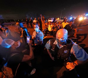 Police officers take a knee alongside protesters who took over the elevated Interstate 10 during a march in New Orleans, Tuesday, June 2, 2020, protesting the death of George Floyd.