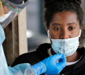 Nyasha Sarju sits as a Seattle Fire Department paramedic prepares to take a nasal swab sample to test for coronavirus at a testing site, Monday, June 8, 2020.