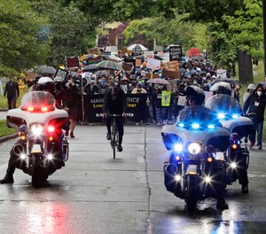 Police on motorcycles ride ahead of protesters taking part in a