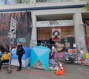Posters and signs are hung on fencing around the East Precinct building of the Seattle Police Department, Sunday, June 14, 2020, inside what has been named the Capitol Hill Autonomous Zone (CHAZ) in Seattle.