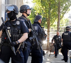 Seattle Police officers stand guard outside the East Precinct Building, Sunday, July 19, 2020 in Seattle.