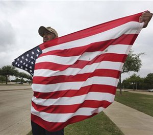 Joseph Offutt, 20, holds a U.S. flag across the street from the Curtis Culwell Center, Tuesday, May 5, 2015, in Garland, Texas.