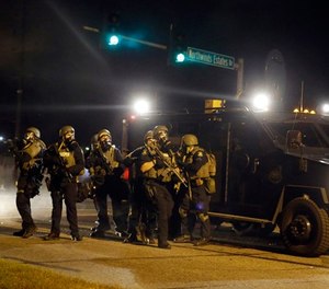 Police take up positions after being shot at Monday, Aug. 18, 2014, in Ferguson, Mo.