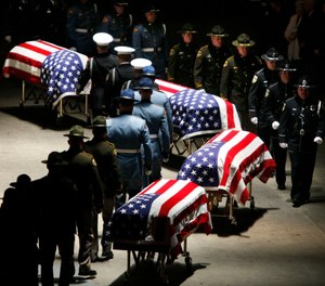 In this Dec. 8, 2009, file photo, police officers approach the caskets of four slain Lakewood police officers as they prepare to fold the flags draped on them during a memorial service at the Tacoma Dome in Tacoma, Wash.