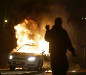 In this Nov. 24, 2014 file photo, a police car is set on fire after the announcement of the grand jury decision in the shooting of Michael Brown in Ferguson, Mo.