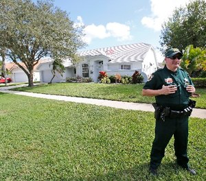 A Palm Beach County Sheriff's deputy keeps watch over the home of Palm Beach Gardens police Officer Nouman Raja, Wednesday, Oct. 21, 2015, in Lake Worth, Fla. (AP Photo/Wilfredo Lee)