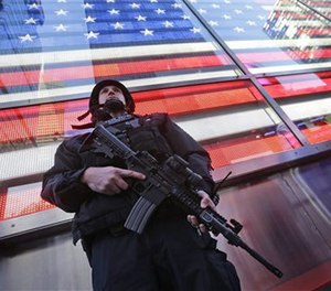 A heavily armed New York city police officer with the Strategic Response Group stands guard at Times Square, Saturday, Nov. 14, 2015