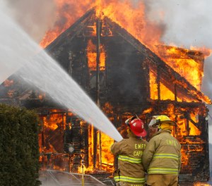 In this Sunday, April 14, 2013 photo, firefighters man a hose line during a training burn in Berlin, Vt.