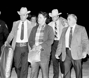 Convicted murderer Henry Lee Lucas is escorted by Louisiana and Texas police officers to a waiting car after arriving by plane in New Orleans, Jan. 8, 1985. Lucas was brought to the New Orleans area at the request of local police officials, hoping he will help solve as many as three dozen murder cases.