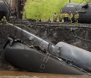 Firefighters and rescue workers work along the tracks where several CSX tanker cars carrying crude oil derailed and caught fire along the James River near downtown in Lynchburg, Va.