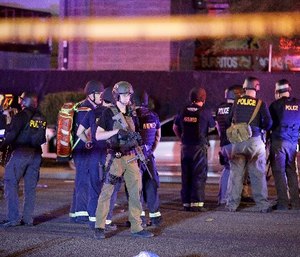 Police officers and medical personnel stand at the scene of a shooting near the Mandalay Bay resort and casino in Las Vegas.