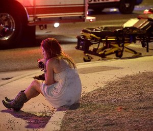 A woman sits on a curb at the scene of a shooting outside of a music festival along the Las Vegas Strip, Monday, Oct. 2, 2017, in Las Vegas. Multiple victims were being transported to hospitals after a shooting late Sunday at a music festival on the Las Vegas Strip.