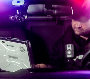 An officer sits in a patrol car mounted with an Axon Fleet 3 in-car video system.