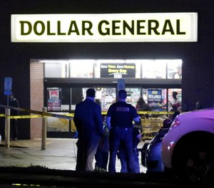 Law enforcement officers surround the Dollar General parking lot, located in the 1100 block of Opelika Road in Auburn, Ala, on Friday, Feb. 15, 2019. The site is the location of where an Auburn police officer was shot that afternoon after stopping a suspect vehicle in an attempted robbery case.