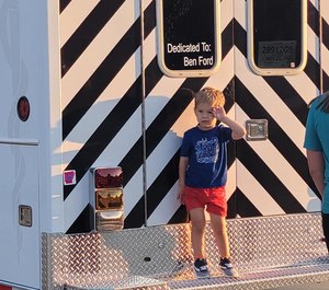 Ben Ford, 3, salutes the Emerson Ambulance Service from the tailboard of the rig dedicated to him.