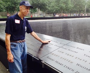 Arnie Roma places his hand next to his son's name at the National 9/11 Memorial in New York City.