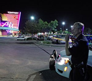 An Aurora police officer talks on his radio outside the Century 16 movie theatre in Aurora (Colo.) on July 20, 2012 during the chaotic response to the mass shooting there.