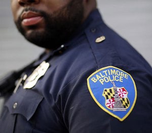 In this March 31, 2016 photo, Baltimore Police Department Officer Jordan Distance stands on a street corner during a foot patrol in Baltimore.