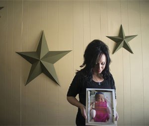 In this Nov. 13, 2014, photo, Jennifer Blaz, 34, poses for a photo in her home in Butte, Mont., holding a photograph of her daughter, Mattisyn Blaz. Earlier that day, Matthew Blaz, 33, was sentenced to life in prison without parole for the death of their infant daughter.