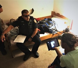 Harris County Sheriff’s Deputy Jose Gomez gives an iPad to a woman for assessment. (Photo/Houston Public Media)