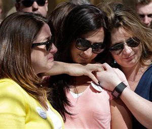 Jenna Dziedzic, left, of Boston, stands with Sabrina Dellorusso, center, also of Boston, and Jillian Boynton, right, of Manchester, N.H., during a moment of silence at one of two blast sites near the finish line of the Boston Marathon, in Boston, Wednesday, April 15, 2015. The women were close to a blast site near the finish line of the Boston Marathon in 2013 where a friend, Roseann Sdoia, lost a limb during the explosion. (AP Photo/Steven Senne)