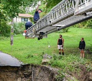 Leominster firefighters use a ladder truck at the site of a bridge washout.
