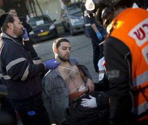 An injured man is treated by paramedics at the scene of a stabbing in Tel Aviv, Israel, Wednesday, Jan. 21, 2015. A Palestinian man stabbed nine people, injuring several seriously, on a bus in central Tel Aviv before he was chased down, shot and arrested, Israeli police said Wednesday, describing the assault as a “terror attack” in the latest in a spate of violence, the worst Israel has seen in almost a decade. (AP Photo/Oded Balilty)
