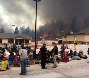 Civilians and first responders utilize a temporary refuge area (TRA) established in a parking lot to stay safe during the Camp Fire.