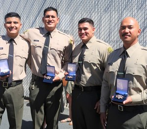 Correctional officer cadets hold their new badges after graduation from Basic Correctional Officer Academy.
