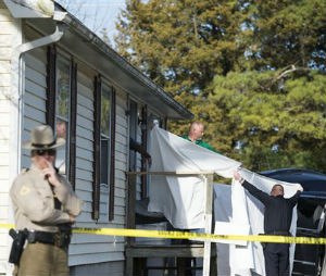 Sheets are held as a body is removed from a residence where police say seven children and one adult have been found dead Monday, April 6, 2015, in Princess Anne, Md. Officers were sent to the home Monday after being contacted by a concerned co-worker of the adult. (AP Photo/The Daily Times, Joe Lamberti)
