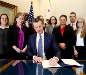 Gov. Gavin Newsom signs the executive order placing a moratorium on the death penalty at his Capitol office Wednesday, March 13, 2019, in Sacramento, Calif.