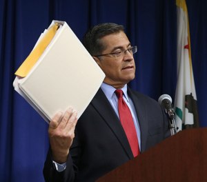 California Attorney General Xavier Becerra displays one of the three binders containing his office's investigation into last year's fatal shooting of Stephon Clark by two Sacramento Police Officers