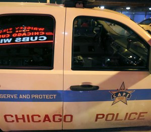 Wrigley Field's marquee message Cub Win is reflected in the window of a Chicago police department vehicle outside the stadium in Chicago (AP Photo/Charles Rex Arbogast)
