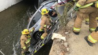 Photos: Crash traps two people in car dangling over rushing Calif. canal