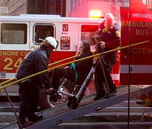 A woman is transported in a wheelchair onto an ambulance bus as people are evacuated from a smoke filled Metro subway tunnel in Washington, Monday, Jan. 12.