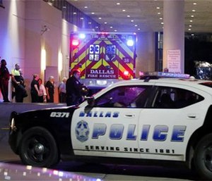 A Dallas police vehicle follows behind an ambulance carrying a patient to the emergency department at Baylor University Medical Center, as police and others stand near the emergency entrance early Friday, July 8, 2016, in Dallas.