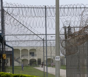 A prisoner works on the lawn at the Dade Correctional Institution on Thursday, July 10, 2014, in Florida City, Fla.